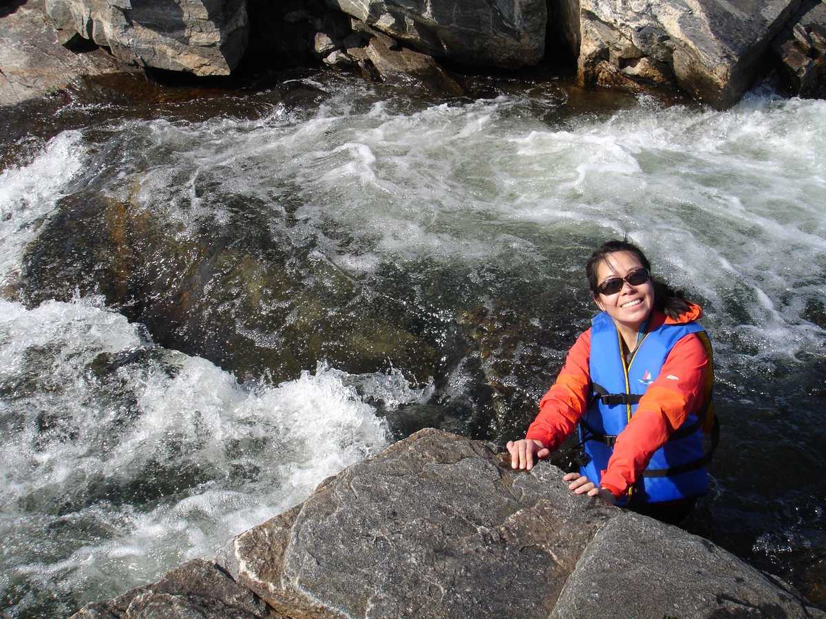 Lilian standing waist-deep in rapids while wearing a life jacket --- Lilian debout jusqu'à la taille dans les rapides tout en portant un gilet de sauvetage