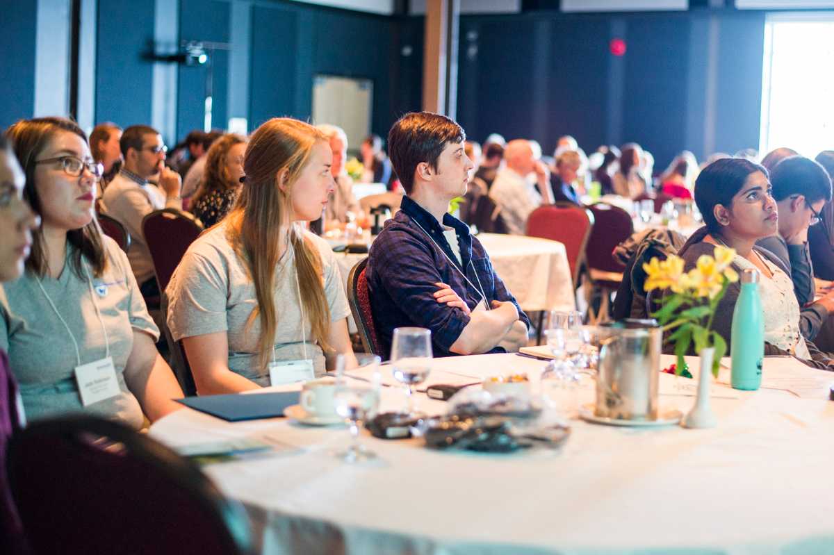 people sitting at a cloth table listening to presenters at the datastream kickoff