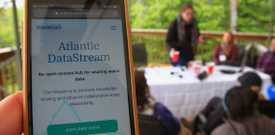 Iphone displaying the Atlantic DataStream homepage with people on a deck around a table in the background